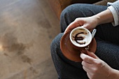 Frau hält Cappuccino mit Euro-Zeichen