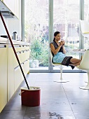 Young woman relaxing, mop in foreground