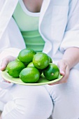 A young woman holding a plate of limes