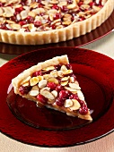 A slice of caramel tart with almonds and cranberries