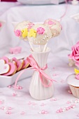 Three cake pops decorated with sugar roses in a vase