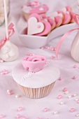 A cupcake with white glaze, sugar rose and sugar pearls