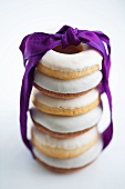 A stack of doughnuts with white sugar icing and a purple gift ribbon