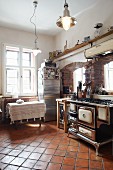 Country house with old kitchen cooker in front of brick archways and terracotta floor tiles