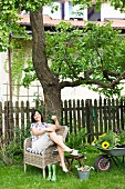 Woman sitting in wicker chair in garden