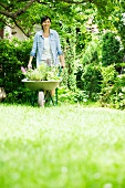 Frau mit Schubkarre im Garten