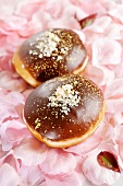 Two chocolate doughnuts on a bed of flower petals