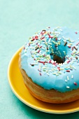 A blue-glazed doughnut decorated with sugar sprinkles
