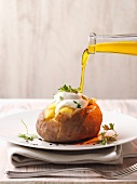 Flaxseed oil being poured onto a jacket potato filled with quark