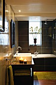 Polierte Wände und schwarze Fliesen im Badezimmer mit Badewanne und Waschbecken
