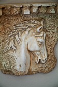 Steinrelief mit Pferdekopfmotiv auf fliederfarbig gestrichener Wand