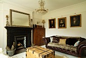 Masculine lounge with open fireplace and dark leather sofa; gilt-framed oil paintings on wall in elegant, rustic atmosphere