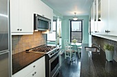 Moderne Einbauküche mit Granitplatten und kleiner Essbereich vor dem Fenster mit Blick auf die New Yorker Skyline
