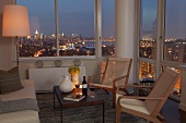 Gemütliche Sitzecke im verglasten Wohnzimmer mit einmaligem Blick über die beleuchtete Skyline bei Nacht