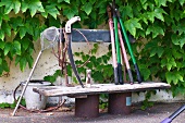 Garden tools on old wooden bench against house facade