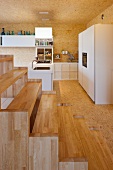 Blick über Treppe aus Holz in offener Küche mit weissen Schrankfronten