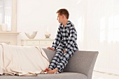 Young boy in pajamas sitting on the back of a sofa