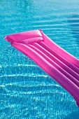 Bright pink lilo in mosaic-tiled pool