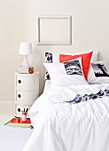 Bed linen with printed motifs on double bed below empty picture frame