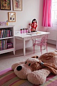 Pink Philippe Starck ghost chair at a desk in a girls bedroom