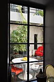 Weisser Eero Saarinen Tisch mit filigranen Stuhlklassikern in bepflanztem Innenhof