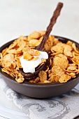 A bowl of cornflakes with a spoonful of yogurt