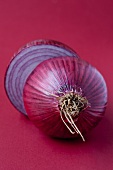 A halved red onion on a red surface