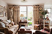 English living room with view of balcony; sumptuous valance curtains, many scatter cushions on sofa and statue of a girl create a nostalgic ambiance