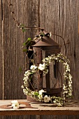 Heart-shaped wreath with white flowers by a rusty lantern