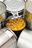 An opened tin of sweetcorn between other tins