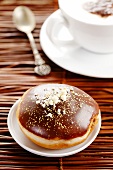 A chocolate doughnut and a cappuccino