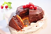 A chocolate cake topped with raspberries, sliced