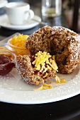 A bran muffin with jam and Cheddar cheese