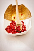 Pink peppercorns in a bowl and on a wooden spoon