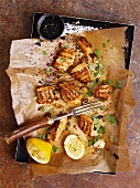 Grilled fish on baking paper on a baking tray (seen from above)