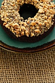 A chocolate and banana doughnut topped with nuts