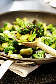Sauteed Broccoli on a Wooden Spoon Over a Skillet