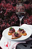 Canapés mit Roastbeef und ein Glas Rotwein