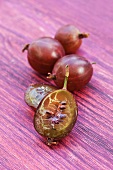 Red gooseberries, one sliced, on a wooden surface