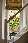 Blick von der Treppe in ein kleines Alkoven mit gemustertem Stoffrollo am Fenster