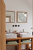 Badezimmer mit langem Waschtisch, zwei Waschbecken und zwei quadratischen, gerahmten Badezimmerspiegeln