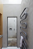 Contemporary towel rack on a raw concrete wall in a minimalist bathroom