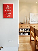 Red and white picture with slogan, sideboard and wooden bench in dining room
