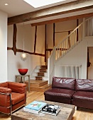 Vintage leather sofa and armchair next to rustic coffee table in living room with half-timbered elements