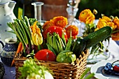 A basket of freshly harvested summer vegetables on a table outside