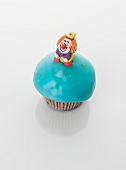 A turquoise cupcake decorated with a clown