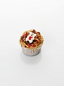 A cupcake decorated with caramel, a teddy bear and hearts