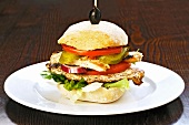 A chicken burger with tomatoes and gherkins
