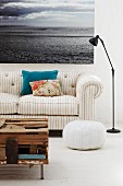 Coffee table made from flotsam, grey and white striped sofa and large seascape photograph on wall