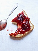 A slice of bread topped with damson jam with a bite taken out
